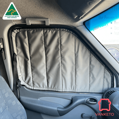 A gray quilted car window shade installed on the driver's side window of a vehicle, shown in a real car interior with the dashboard, door panel, and seat visible. Brand logos for Vanketo and Australian Made and Vouched are displayed on the image.