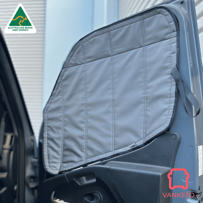 A gray padded car window shade installed on the open door of a vehicle, shown in a real outdoor setting with a building facade in the background. A Vanketo logo appears in the bottom right corner, and an Australian Made and Vefined badge appears in the top left.