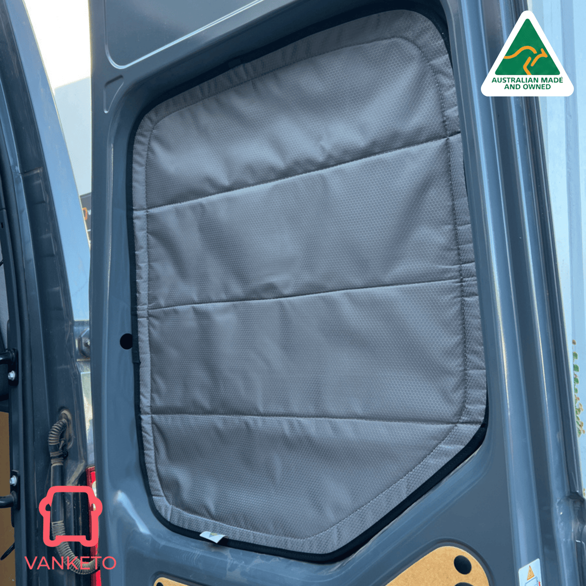 A gray padded van door window shade installed inside a vehicle door, shown in use on a dark blue-gray van with an Australian Made and Vanketo logo overlay.